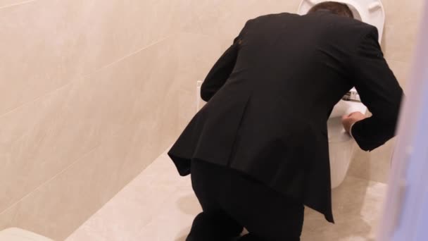 A drunken man in business clothes vomits into the toilet. This symptom may be accompanied by abdominal pain and diarrhea. Problems of alcohol addiction - Felvétel, videó