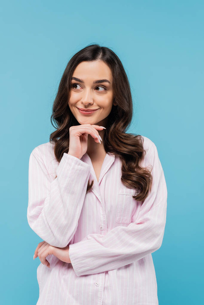 smiling young woman in sleepwear looking away isolated on blue  - Photo, Image
