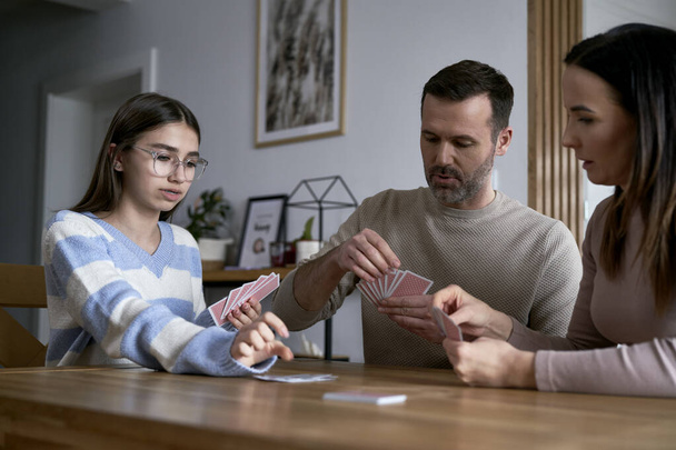 Caucasian family playing in card together and relaxing at home - Foto, Bild