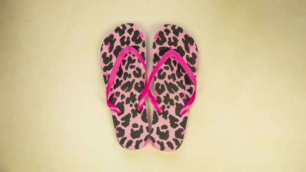 Bright women's flip flops on a colorful yellow background moving from left to right top view, pink panther pattern spring,summer concept - Felvétel, videó