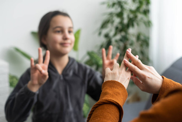daughter talk with middle aged mother people using sign language, family sitting on armchair side view, teacher teach teenager deaf-mute girl to visual-manual gestures symbols concept image. - Valokuva, kuva