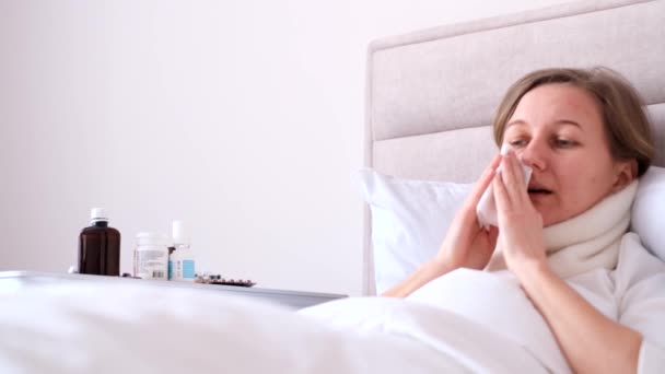Behandeling van griep thuis. Een zieke vrouw ligt in bed. Begrip gezins- en ziektekostenverzekering. 4k video - Video