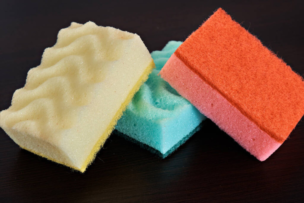 Multicolored kitchen sponges for washing dishes on a dark background. - 写真・画像