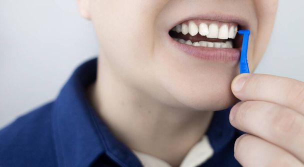 Szczotka. Mężczyzna pokazuje szczotkę do czyszczenia przestrzeni międzyzębowej. Szczotka do czyszczenia zębów i codziennej pielęgnacji jamy ustnej. Stomatologia i ortodoncja  - Zdjęcie, obraz