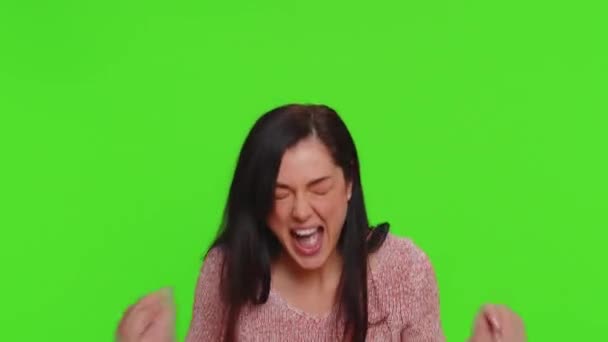 Young woman in sweater screams from stress tension problems feels horror hopelessness fear surprise shock expresses gestures rage. Pretty brunette girl indoors isolated alone on chroma key background - Felvétel, videó