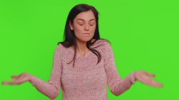 I dont know what to say. Confused woman feeling embarrassed about ambiguous question, having doubts, no idea, being clueless and uncertain. Young pretty girl isolated on green chroma key background - Záběry, video
