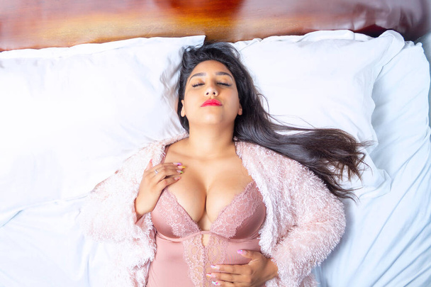 sexy hispanic vrouw in lingerie liggend op bed - Foto, afbeelding