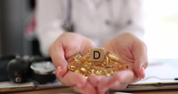 Желтые капсулы витамина D3 в руках врача крупным планом. Здоровое питание, поддержка организма, замедление - Кадры, видео