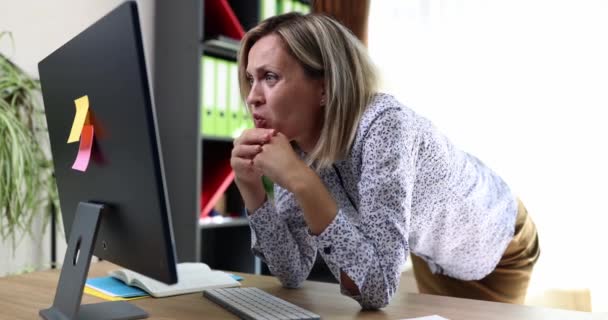 Een jonge vrouw in het kantoor op een computer monitor grijpt haar hoofd, close-up. Bedrijfsfout, problematisch op het werk - Video