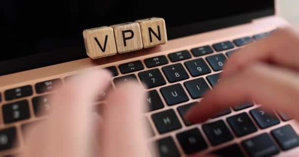 VPN inscription on wooden cubes on the laptop keyboard, close-up, slowmotion. A woman uses the application - Materiał filmowy, wideo
