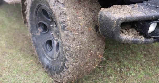 Close-up car with a dirty wheel on the grass, slowmotion. Road without asphalt, the front of the SUV in the swamp - Filmagem, Vídeo