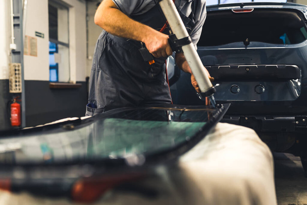 Mechanic adding glue to the windscreen of a car windshield replacement station. High-quality photo. - Photo, image