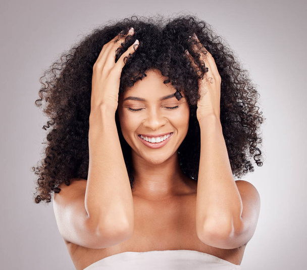 Hair care, health and black woman with an afro in studio touching her hair after salon treatment. Cosmetic, beauty and happy female model with healthy, natural and curly hairstyle by gray background - 写真・画像