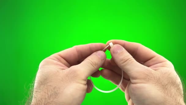 On a green background, a chromakey man fastens a nylon tie with his own hands. He pulls the long end through the hole and secures it nylon tie - Filmati, video