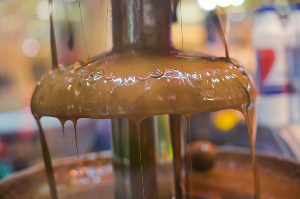 Vibrant Picture of Chocolate Fountain Fontain on childen kids birthday party with a kids playing around and marshmallows and fruits dip dipping into fountain - 写真・画像