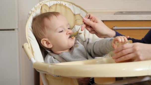Closeup of little baby boy getting messy while eating porridge in highchair. Concept of parenting, healthy nutrition and baby care - Video