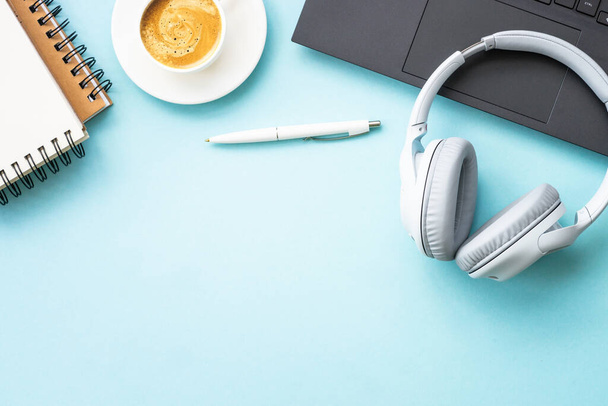 Espacio de trabajo de oficina con laptop, auriculares, bloc de notas y taza de café. Plana imagen de la puesta en azul con espacio de copia. - Foto, imagen