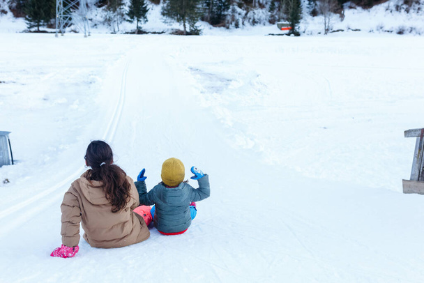 two girls preparing to slide down the snow hill in the mountains - Foto, Imagen