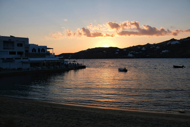 View of a beautiful sunset at the Mylopotas beach in Ios Greece and a fish tavern in the background - Foto, imagen