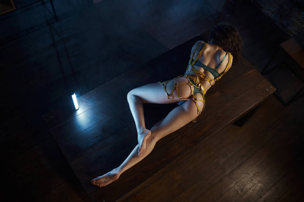 Kilátás felülről a nő tökéletes test erotikus csipke fehérnemű fekvő fa asztalon. Glamour lövés barna szivattyús zsákmány, vékony lábak és illeszkedjen vissza - Fotó, kép