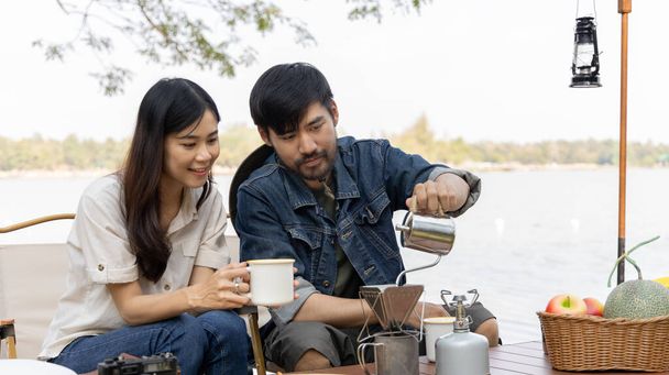 Young couple camping weekend in the woods near river, Enjoying Camping Holiday In Countryside, Leisure activities, Dating and relaxation in nature, Couple dripping coffee and sipping coffee. - Photo, Image