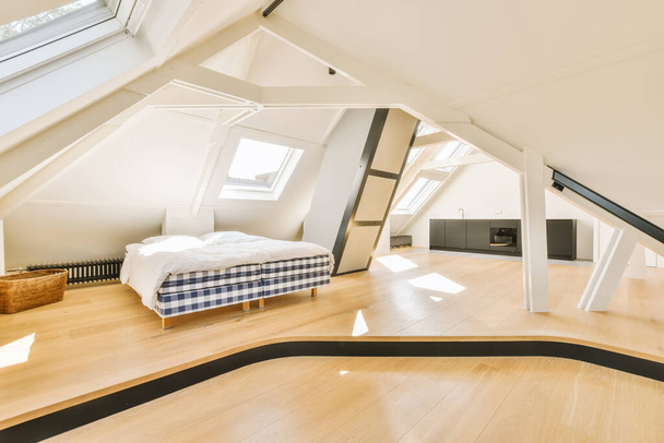 Yatağın üstünde ahşap zemin ve tavan pencereleri olan tavan arası yatak odası. Bu fotoğrafta olduğu gibi. - Fotoğraf, Görsel