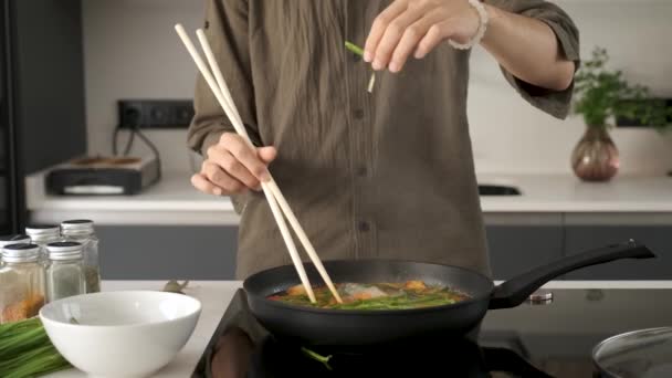 Close up of asian young man hands adding chive to prepare chinese or taiwanese tomato scrambled eggs at kitchen. - Filmagem, Vídeo