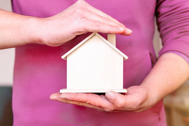 Žena držící a zakrývající model domu rukou - Fotografie, Obrázek