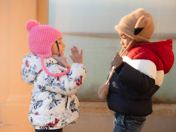Crianças afro-americanas felizes estão andando brincando em um parque de inverno do país, perto de uma floresta ao pôr do sol, diversão de inverno, conceito de estilo de vida ativo. - Foto, Imagem