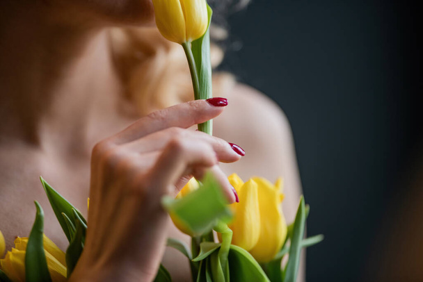 大人の美しさの女性の半分裸の正式な夜の赤いズボンの黄色のチューリップのブラジャー巨大な花束なし。スタイリッシュなブロンド巻き毛官能的なヌードモデルファッショニスタポーズでスタジオで春休み - 写真・画像