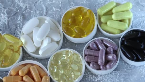Meerdere medicijnen. gesorteerd in kleine platen of deksels van de knoppen op een grijze achtergrond. Populaire medicijnen en pillen. - Video