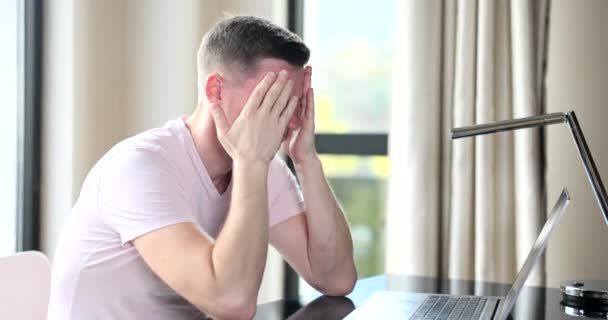 Man met hoofdpijn zittend op laptop scherm op de werkplek 4k film slow motion. Moeilijkheden op het werk - Video