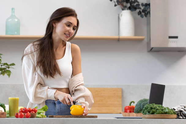 An attractive woman is watching a cooking class on cooking a vegetarian dish. Video recipe, healthy food concept. - Fotoğraf, Görsel