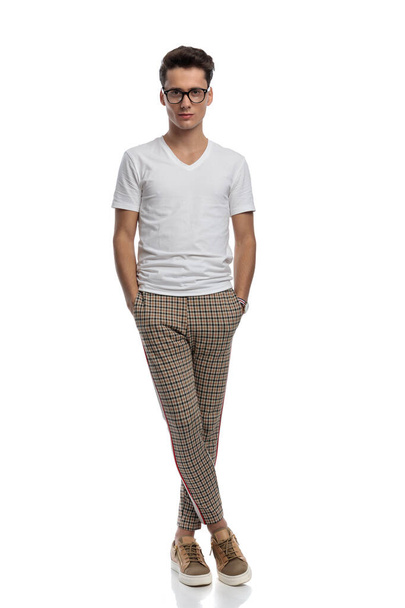 full body picture of confident casual guy holding hands in plaid pants and smiling while posing isolated in front of white background in studio - Fotografie, Obrázek