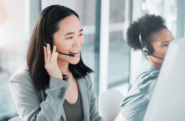 Call center, consulting and asian woman at computer in office for customer service, telemarketing and help desk. Happy, smile and contact us with consultant for technical support, advisory and sales. - 写真・画像
