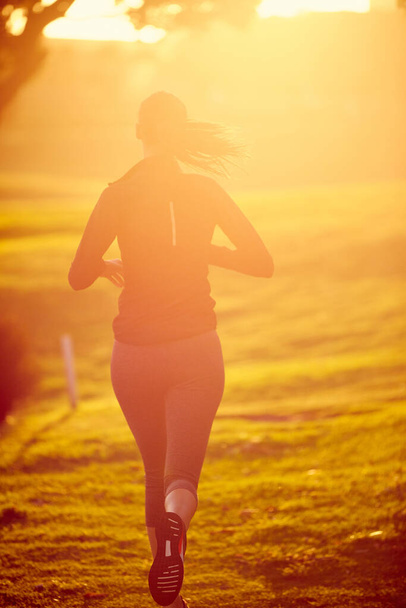 Τρέχοντας προς την καλύτερη υγεία και ευημερία. Στιγμιότυπο μιας αθλητικής νεαρής γυναίκας που γυμνάζεται σε εξωτερικούς χώρους - Φωτογραφία, εικόνα
