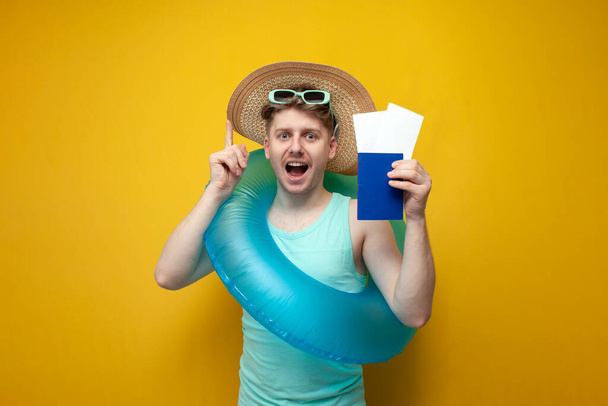 молодой парень летом на отдыхе с паспортом и билетами показывает большой палец вверх на желтом фоне, у меня есть идея - Фото, изображение