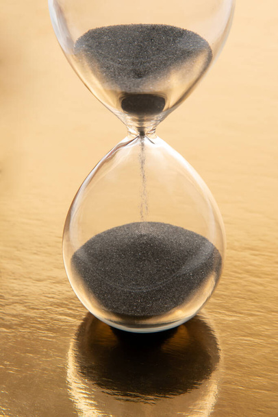 hourglass on a golden background. time and minute measurement - Foto, Imagen