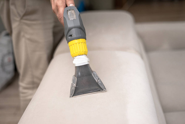 Egy koszos kanapét takarítani egy kanapé mosóval. Közelről, kézen fogva a kanapé tisztítót. Professzionális kanapé mosás. Sofa mosás kép - Fotó, kép