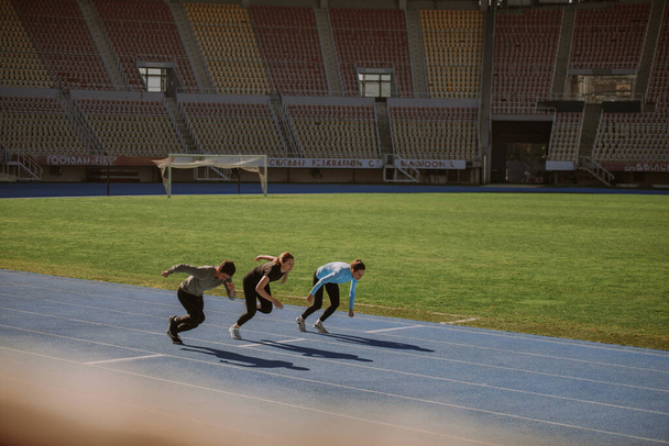 Two females and one male guys just started sprinting at the stadium - Foto, immagini
