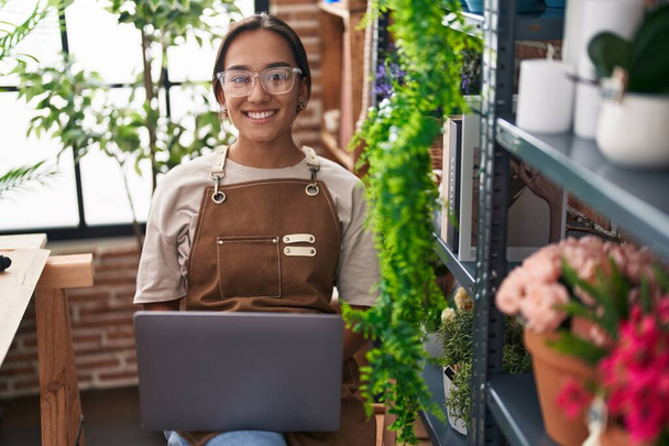 Nuori kaunis latino nainen kukkakauppa hymyilee luottavainen käyttämällä kannettavaa tietokonetta kukkakauppa - Valokuva, kuva