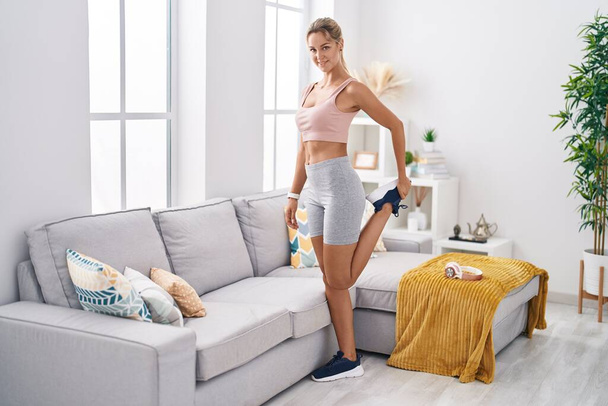 Young blonde woman smiling confident stretching leg at home - Photo, Image