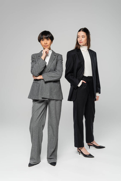 full length of middle aged asian woman with stylish daughter posing on grey background - Fotoğraf, Görsel