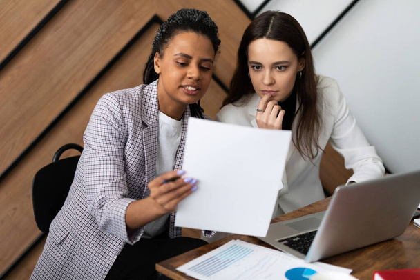 Üzleti nők a munkahelyen tárgyalnak az üzletről egy laptoppal és dokumentumokkal a kezükben.. - Fotó, kép