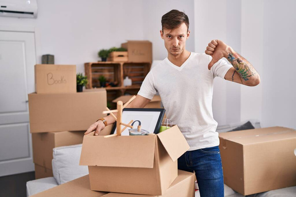 Caucasian man holding screwdriver at new home with angry face, negative sign showing dislike with thumbs down, rejection concept  - Photo, image