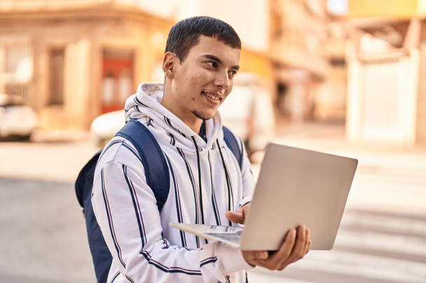 Young man student using laptop standing at street - Foto, imagen