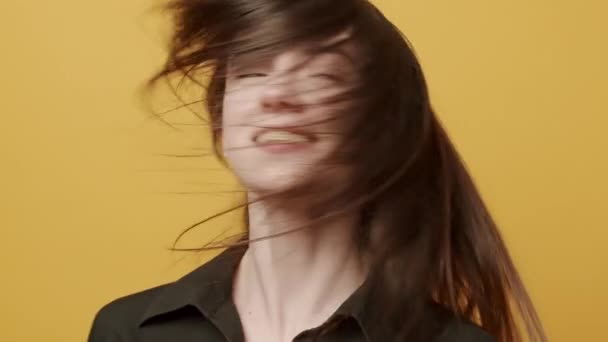 The young woman with flying hair looks on with a smile, happy. touches her hair slowly on yellow background. Cute Girls excited . - Footage, Video