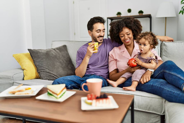 Couple and daughter having breakfast sitting on sofa at home - Fotoğraf, Görsel