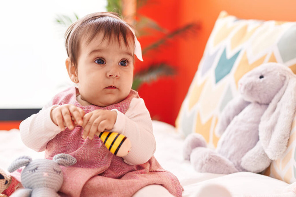 Imádnivaló spanyol baba játszik maraca ül az ágyon a hálószobában - Fotó, kép