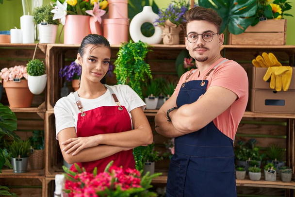 Man and woman florists smiling confident standing with arms crossed gesture at flower shop - Foto, Bild